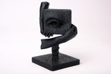 The Witness – surrealistisk skulptur på ett mörkt skrivbord i trä med minimalistisk inredning