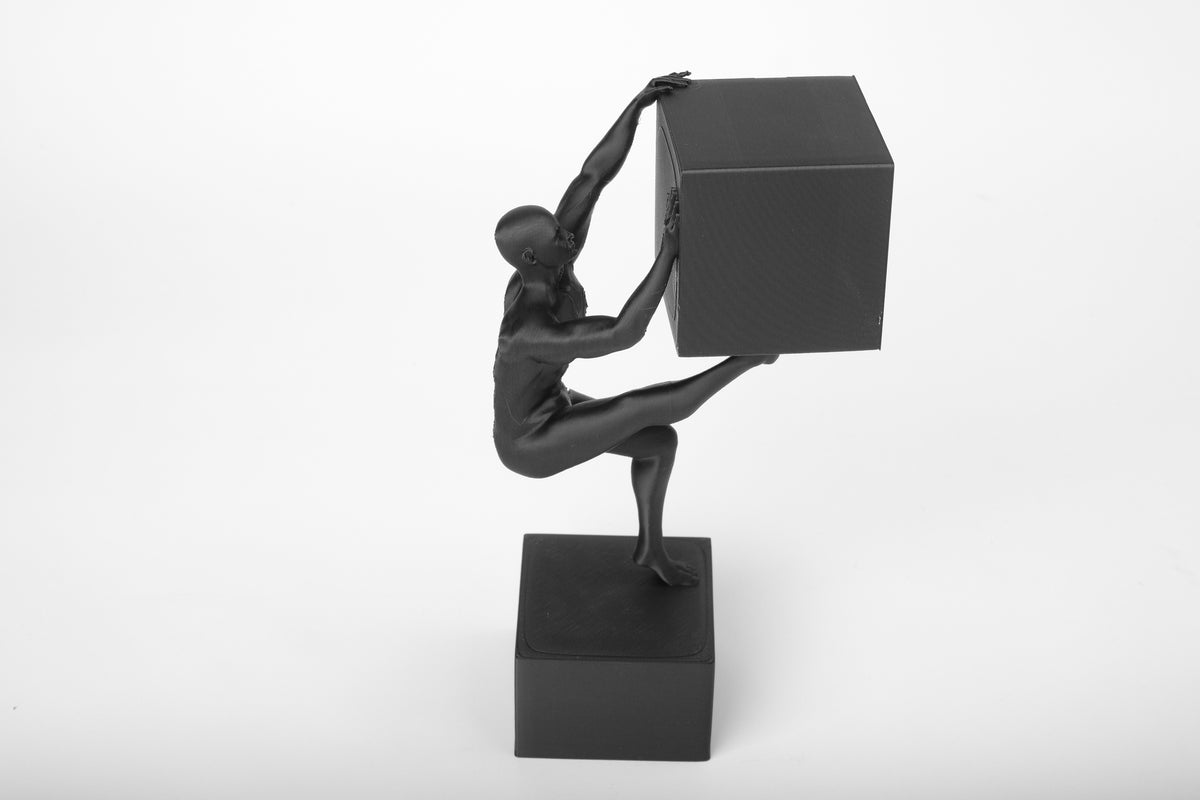 Abstrakt människoskulptur på ett skrivbord i trä bredvid böcker och en keramikmugg i en minimalistisk miljö