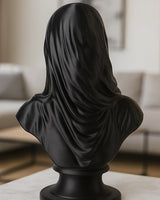 Mattsvart beslöjad byst på vit yta, närbild av slöjans draperade struktur