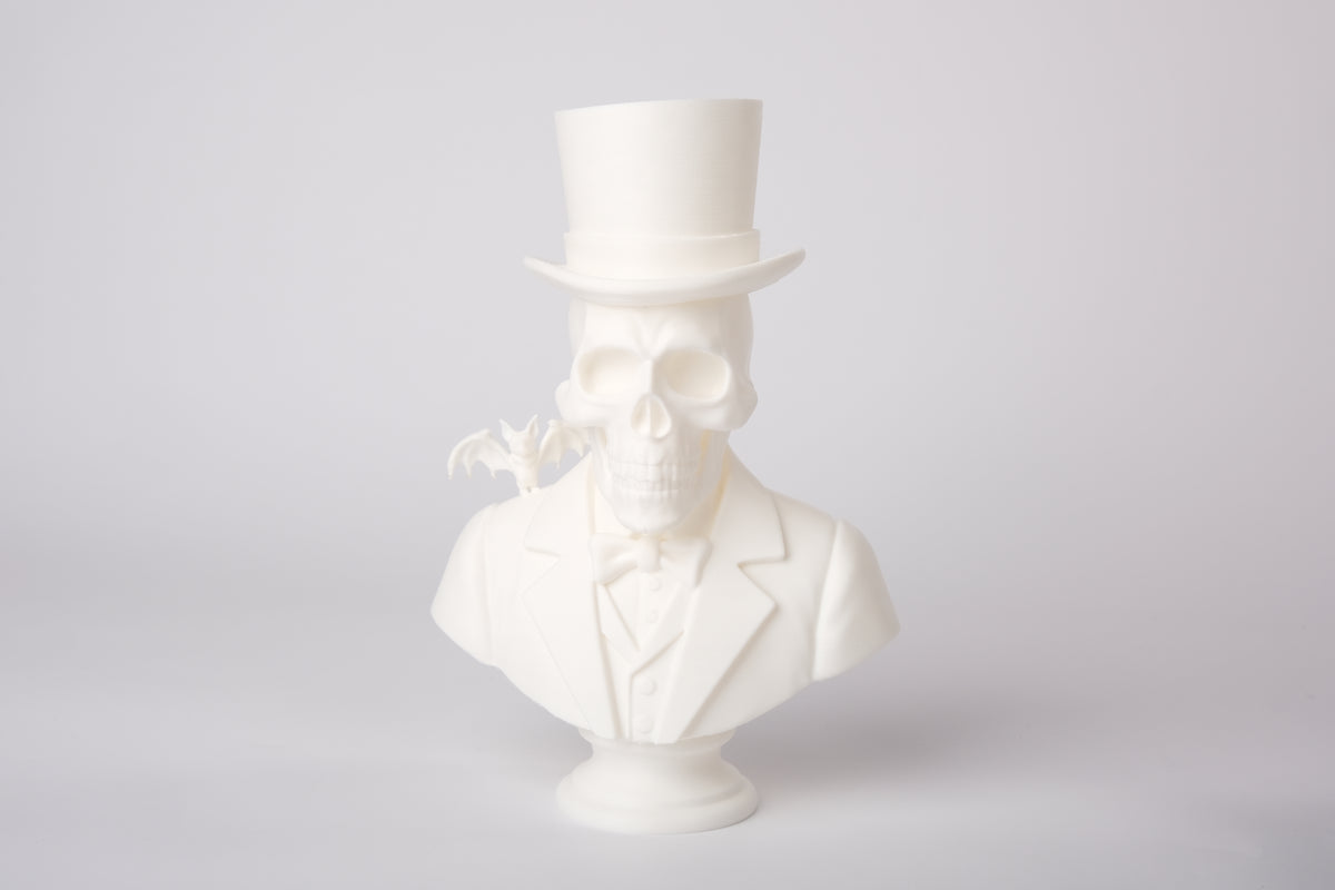 Gotisk skelettskulptur på mörk trähylla med ljus och torkade växter