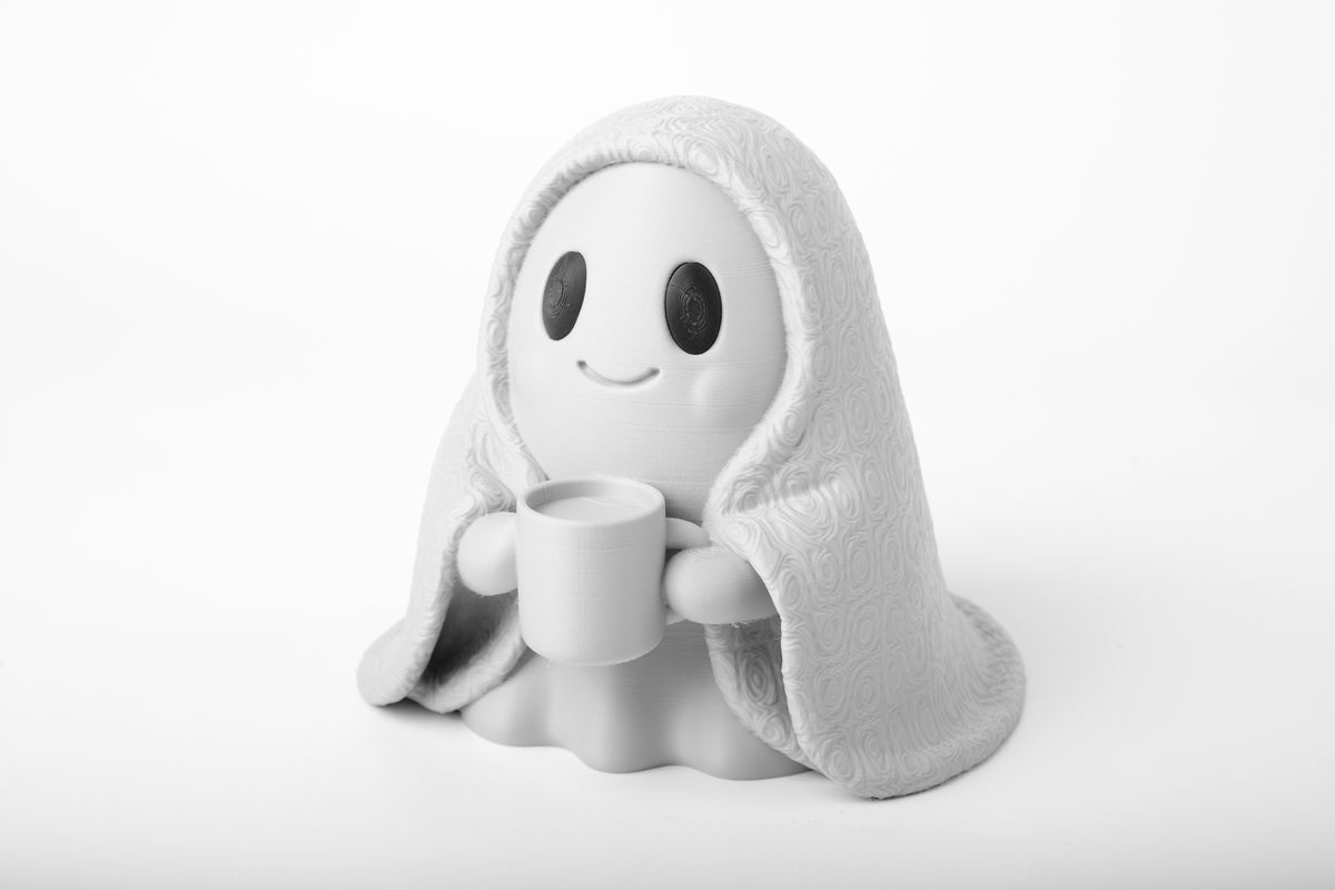 Mysig spökfigur på ett skrivbord i trä bredvid en liten växt och böcker i varmt ljus