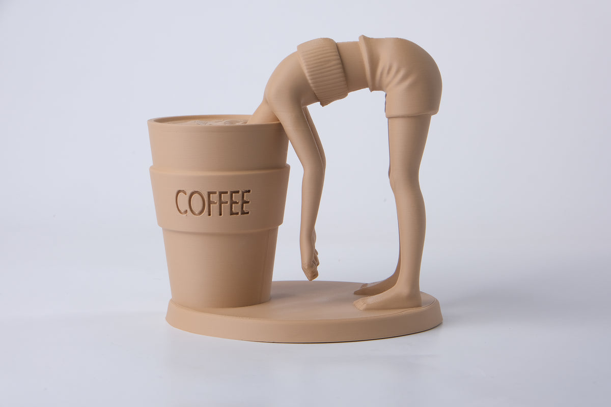 Surrealistisk kaffeskulptur på ett skrivbord i trä bredvid en keramikmugg och en liten växt