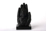 Buddhahandskulptur på en trähylla bredvid ljus och torkade växter i en lugn meditationshörna