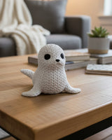 Närbild av en dekorativ stickad sälfigur med virkad look och små mörka ögon
