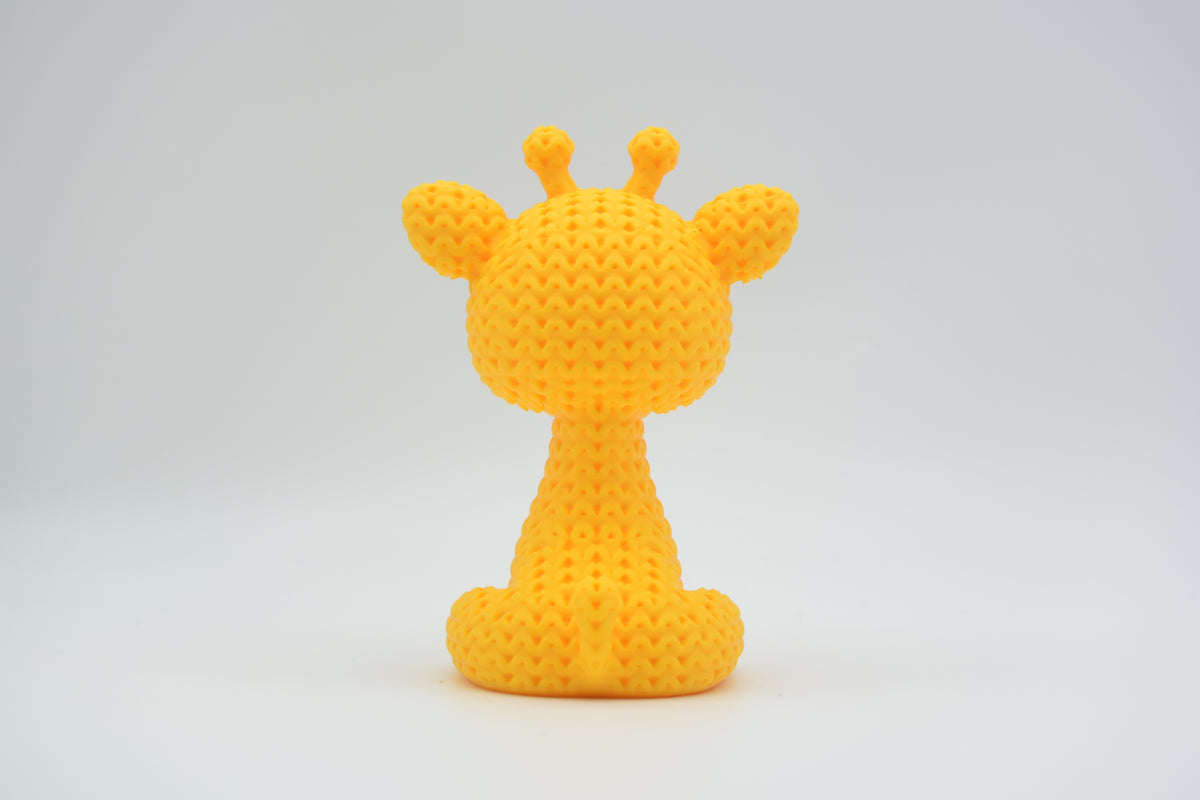 Närbild av en liten stickad girafffigur med virkad textur och uttrycksfulla ögon, ca 8 cm hög