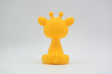 Närbild av en liten stickad girafffigur med virkad textur och uttrycksfulla ögon, ca 8 cm hög