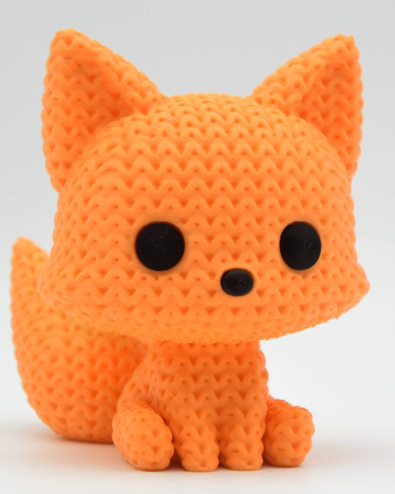 Närbild av en liten stickad rävfigur med masktextur, handplacerade ögon och nos, 6 cm hög