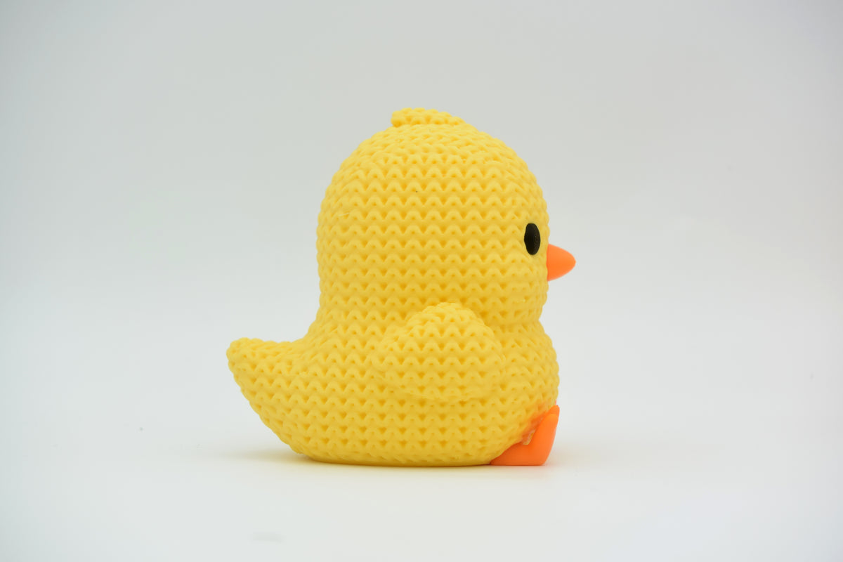 Närbild av en liten gul stickad kyckling med orange näbb och fötter