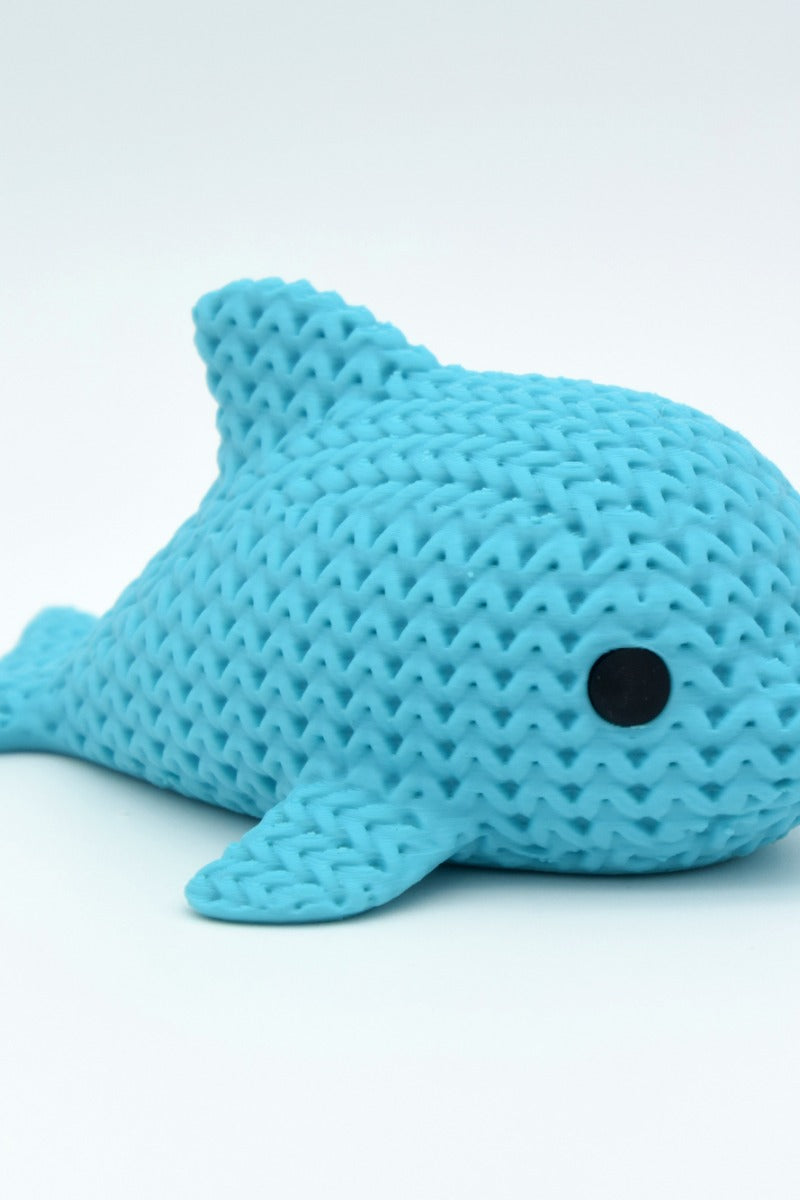 Närbild av en liten stickad delfinfigur med virkad textur och runda infällda ögon
