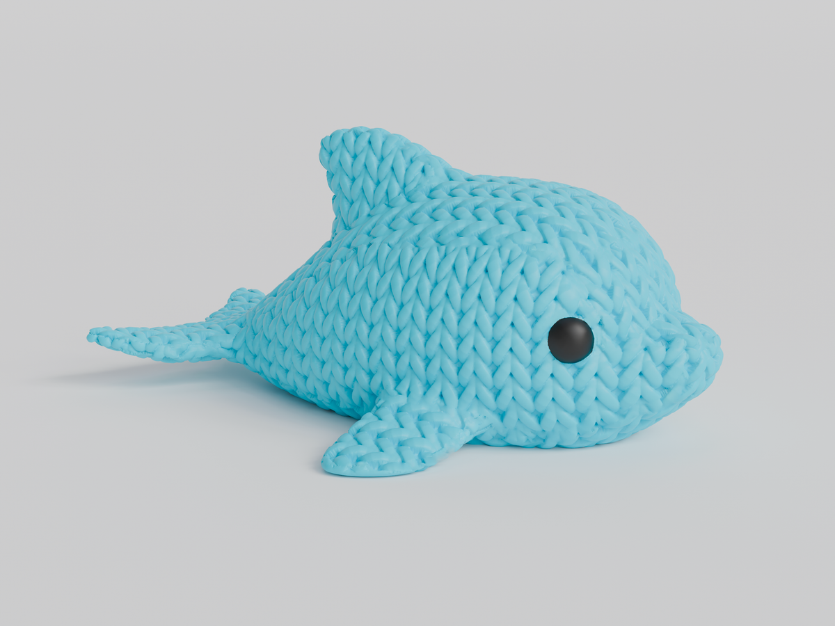 Närbild av en liten stickad delfinfigur med virkad textur och runda infällda ögon