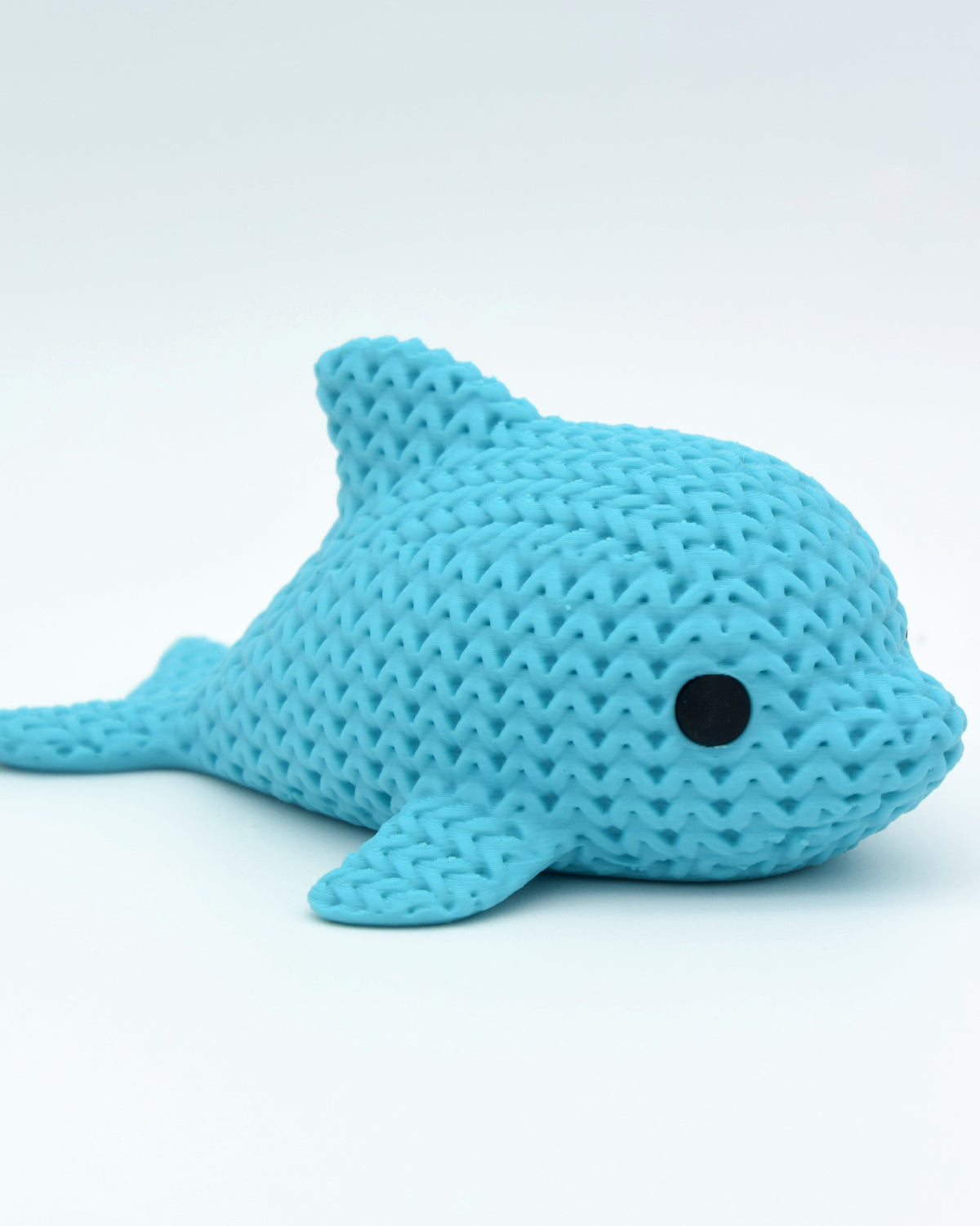 Närbild av en liten stickad delfinfigur med virkad textur och runda infällda ögon