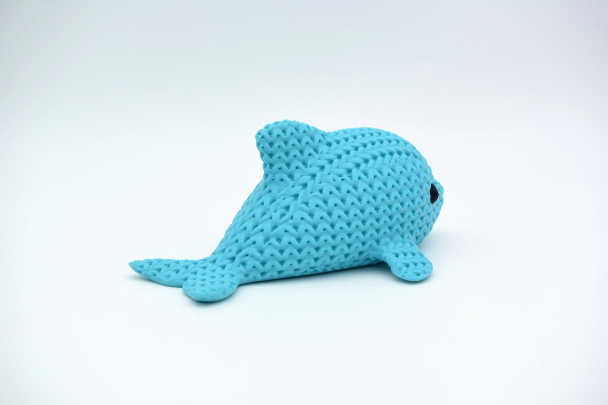 Närbild av en liten stickad delfinfigur med virkad textur och runda infällda ögon