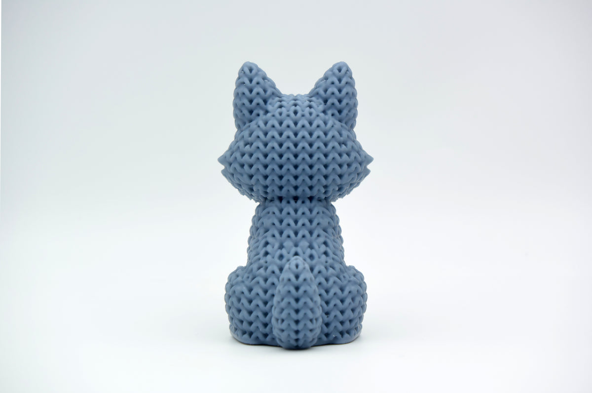 Närbild av en stickad vargfigur med virkad textur i varmgrått, ca 10 cm hög
