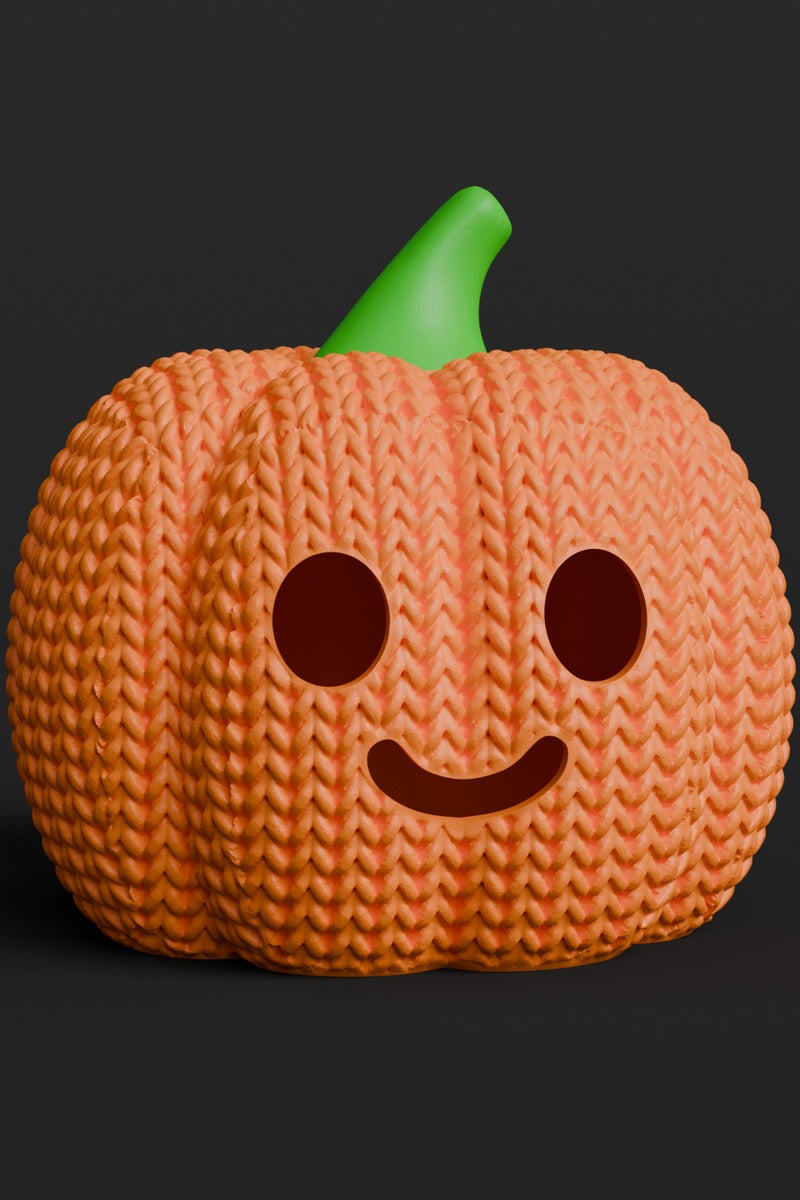 Närbild av en stickad halloweenpumpa med pumpaansikte och mjuk orange textur