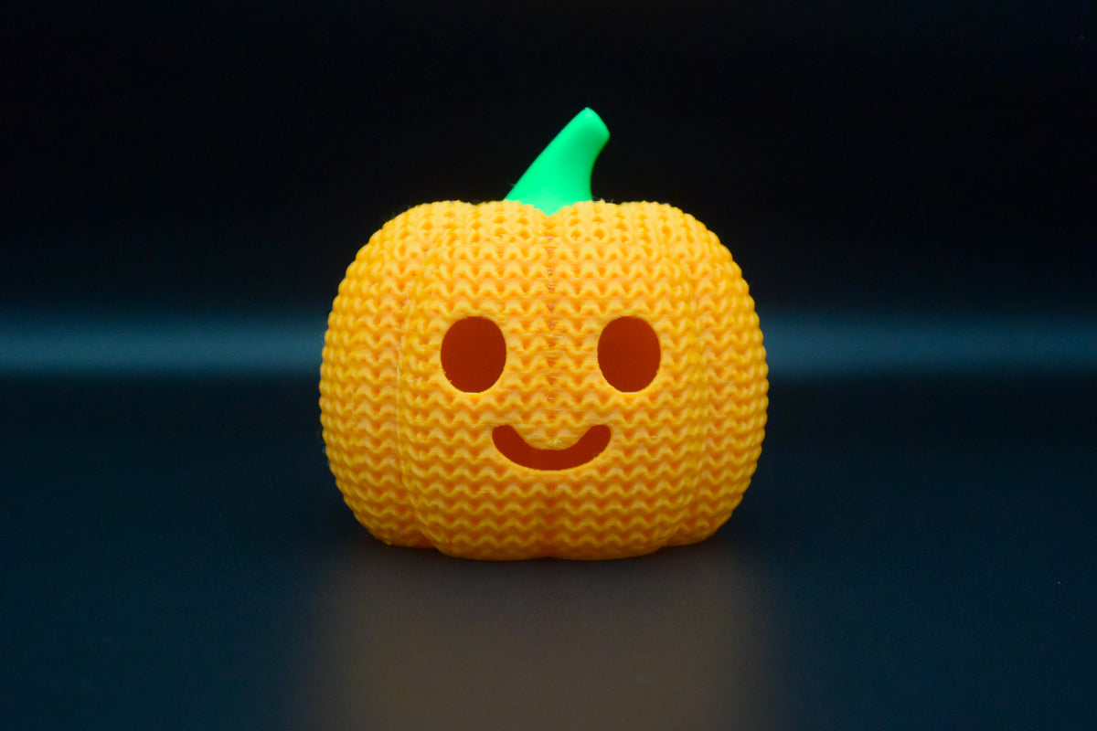 Strukturdetalj av en stickad halloweenpumpa med vävt mönster och utskuret ansikte