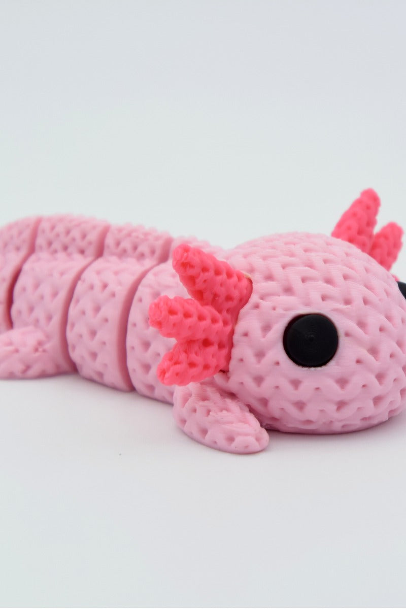 Närbild av en stickad axolotlfigur i ljusrosa med virkad textur
