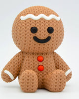 Närbild av en stickad pepparkaksgubbe med vit glasyr och mjuk vävd textur