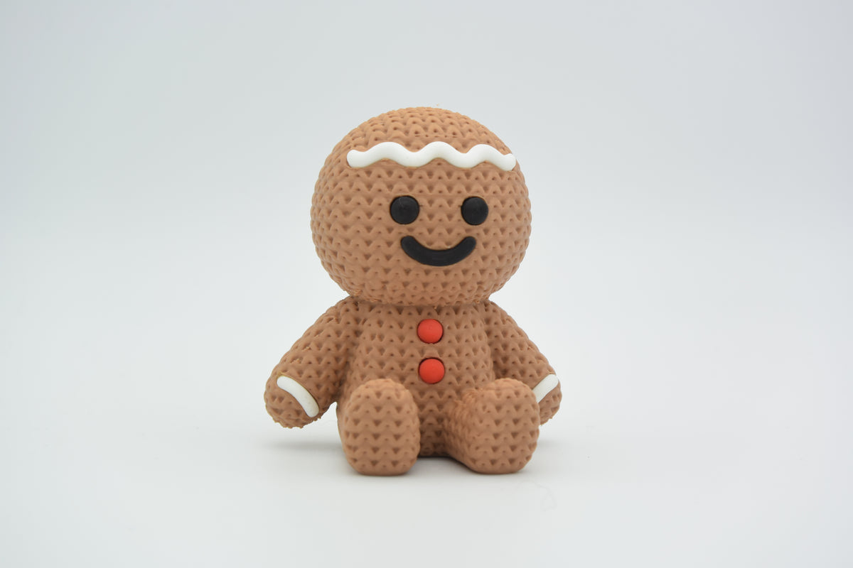 Närbild av en stickad pepparkaksgubbe med vit glasyr och mjuk vävd textur