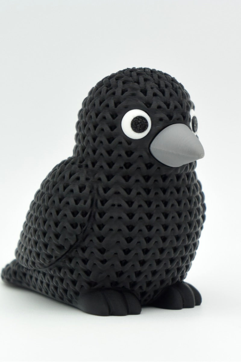 Närbild av en stickad kråkfigur med virkad look och detaljerade klickögon