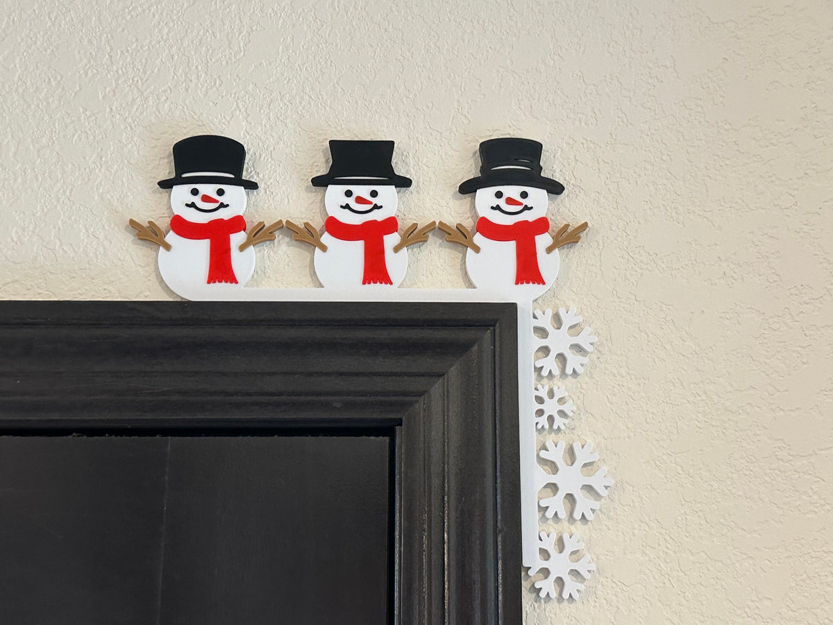 Snögubbar och snöflingor som dekoration i dörrkarmens hörn